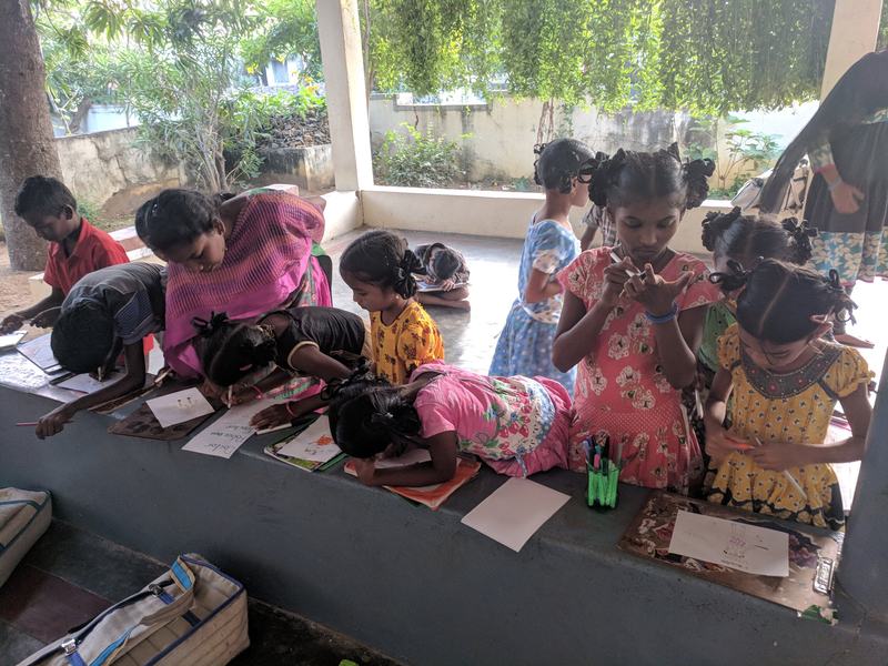 Children writing, laid out along a low wall at a centre